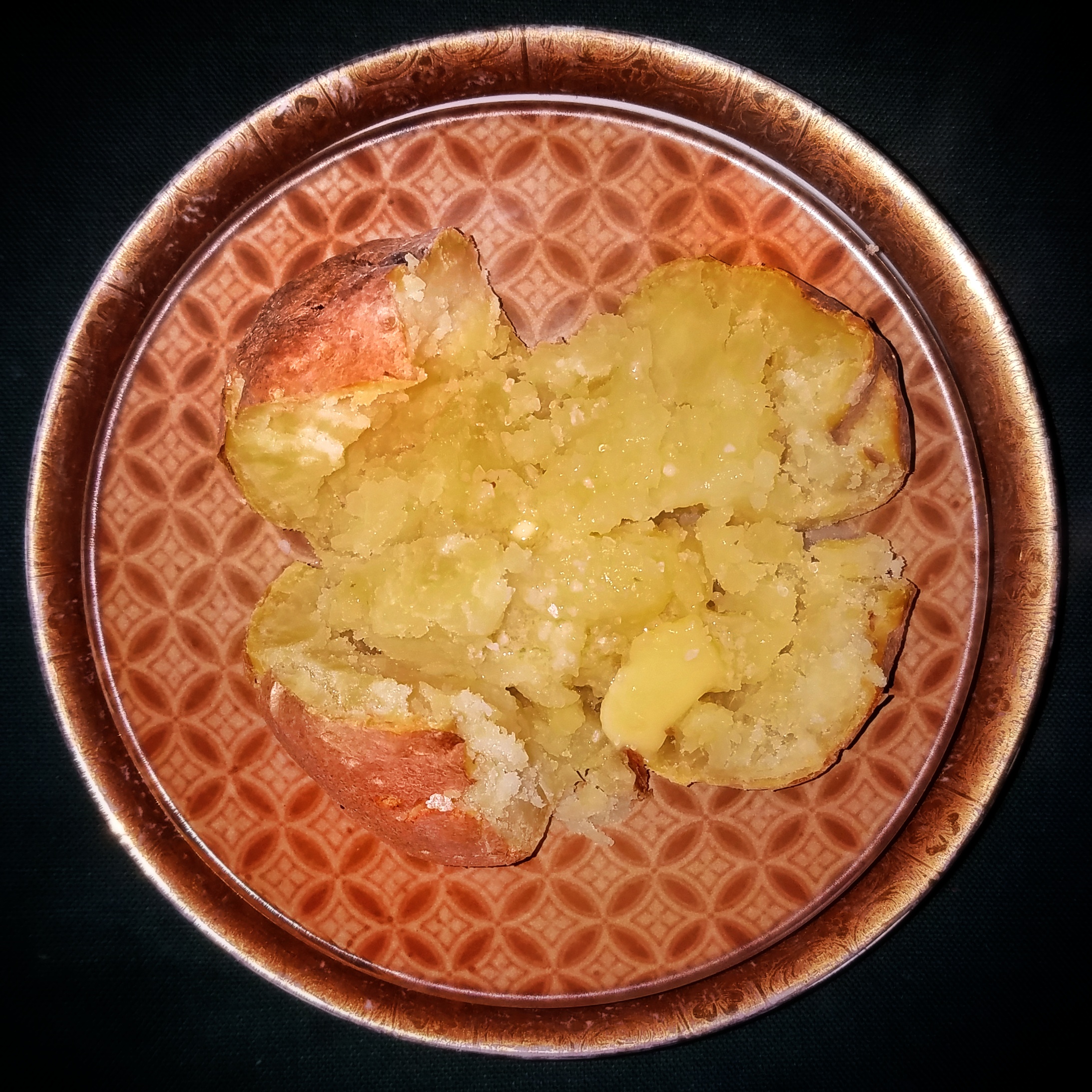 Plain baked potato opened with butter and salt