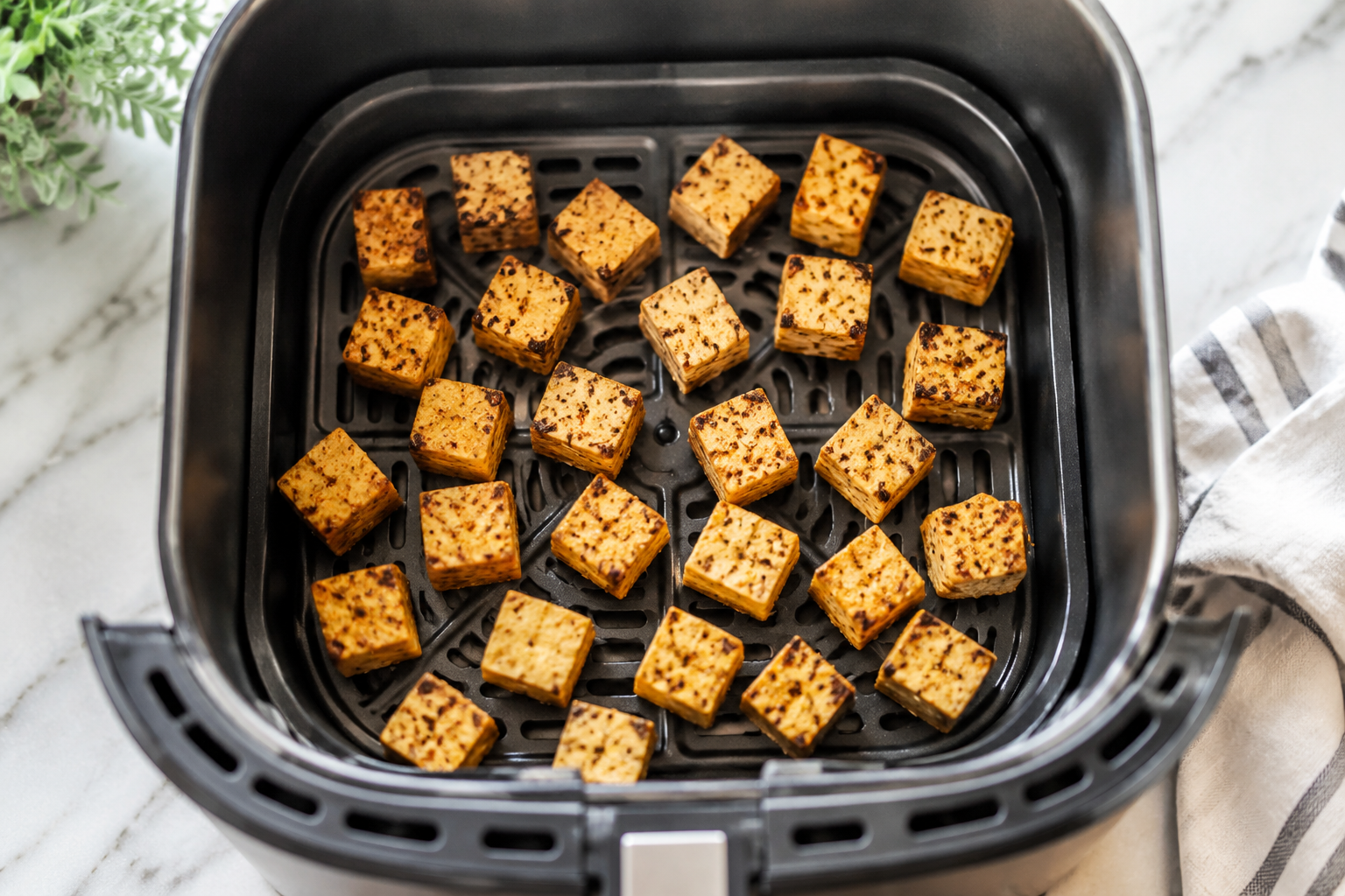 Seasoned tofu cubes arranged in one layer in an air fryer basket