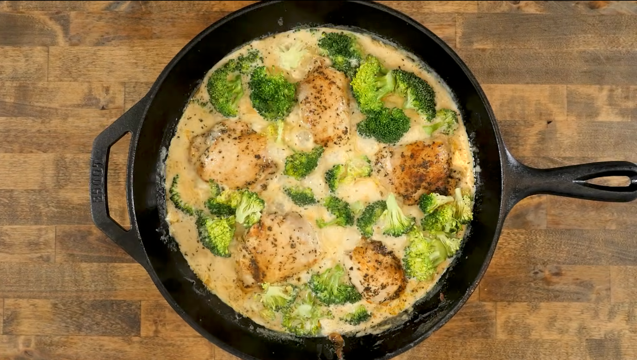 Overhead view of creamy garlic Parmesan chicken and broccoli in a cast-iron pan