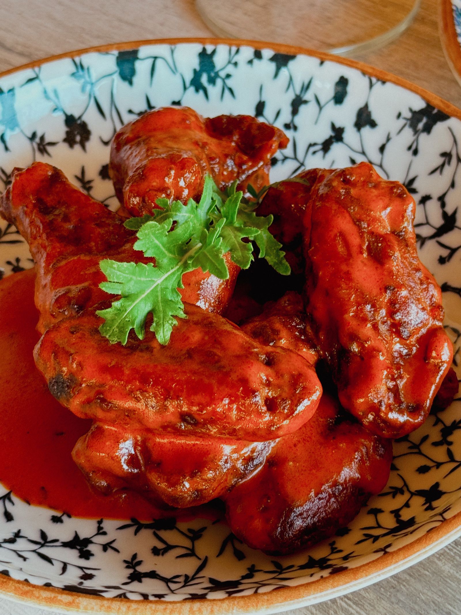 Delicious spicy chicken wings covered in red sauce topped with fresh parsley