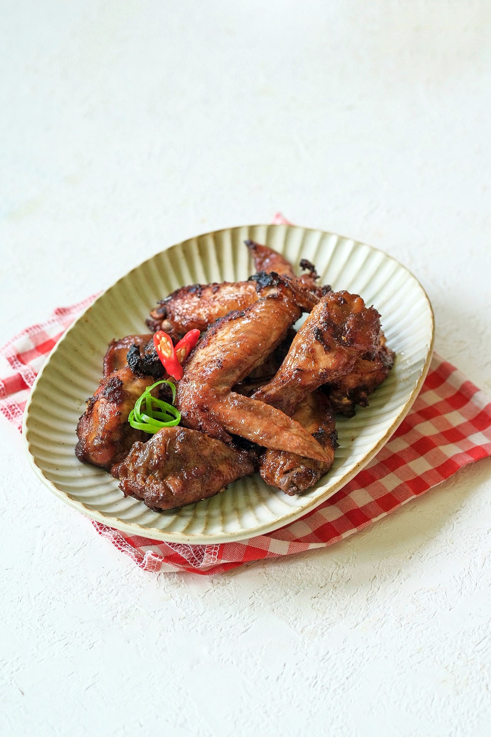 Chicken wings garnished with chilli and spring onion in a bowl