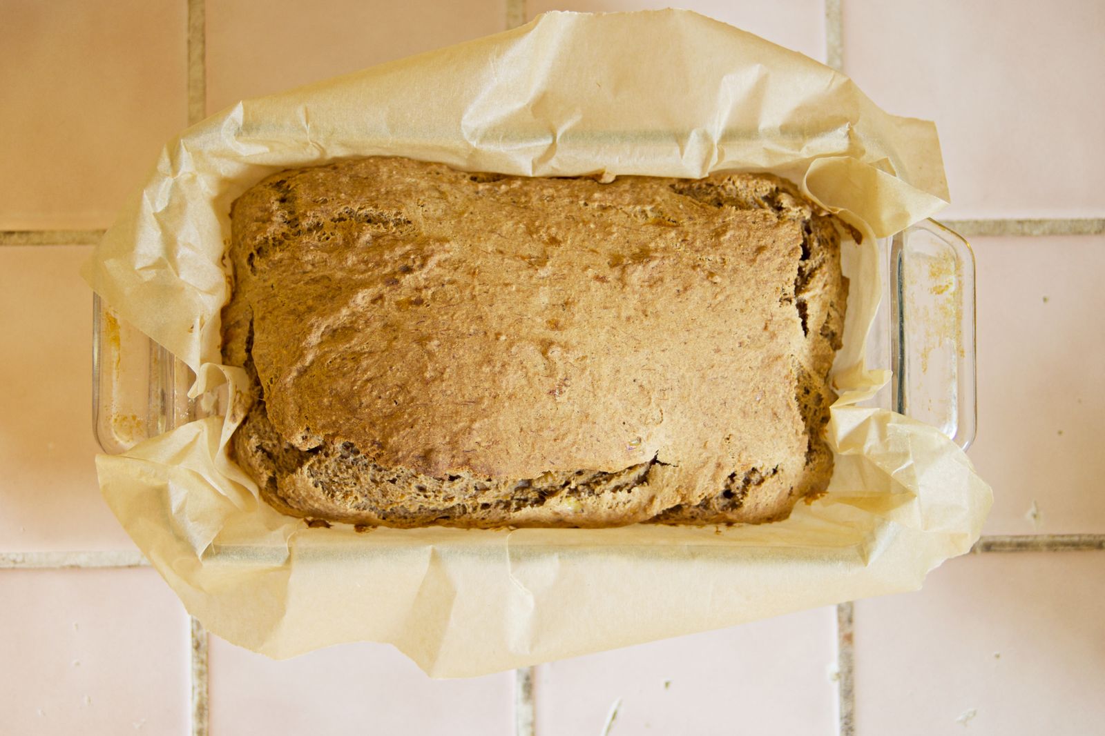 Baked banana bread cooling in the loaf pan lined with baking paper