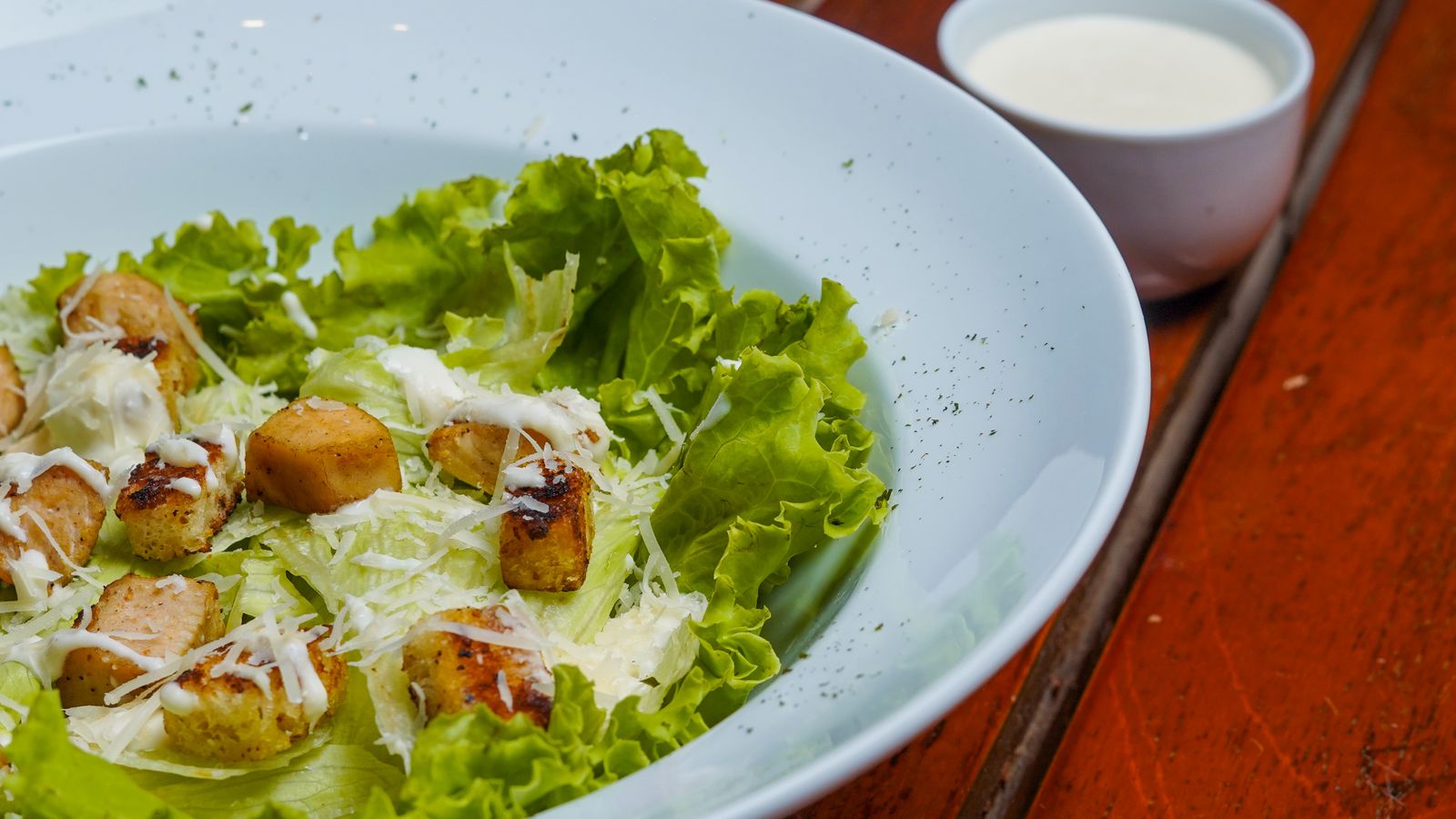 Fresh Caesar salad with crisp lettuce, croutons and cheese in a white bowl