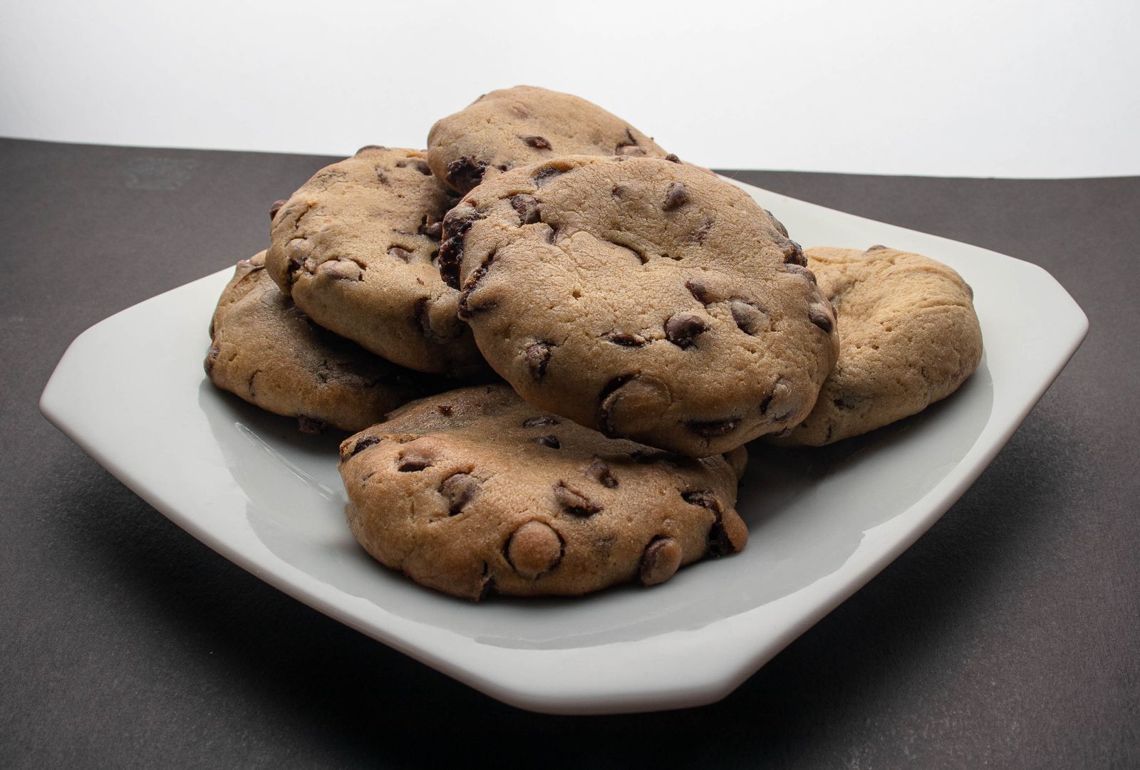 Golden chocolate chip cookies with melted chocolate cooling on a plate