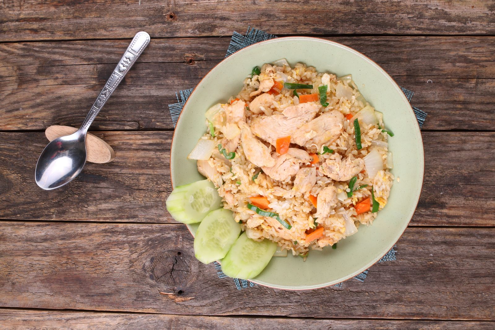 Top view of chicken fried rice with vegetables on a rustic wooden table
