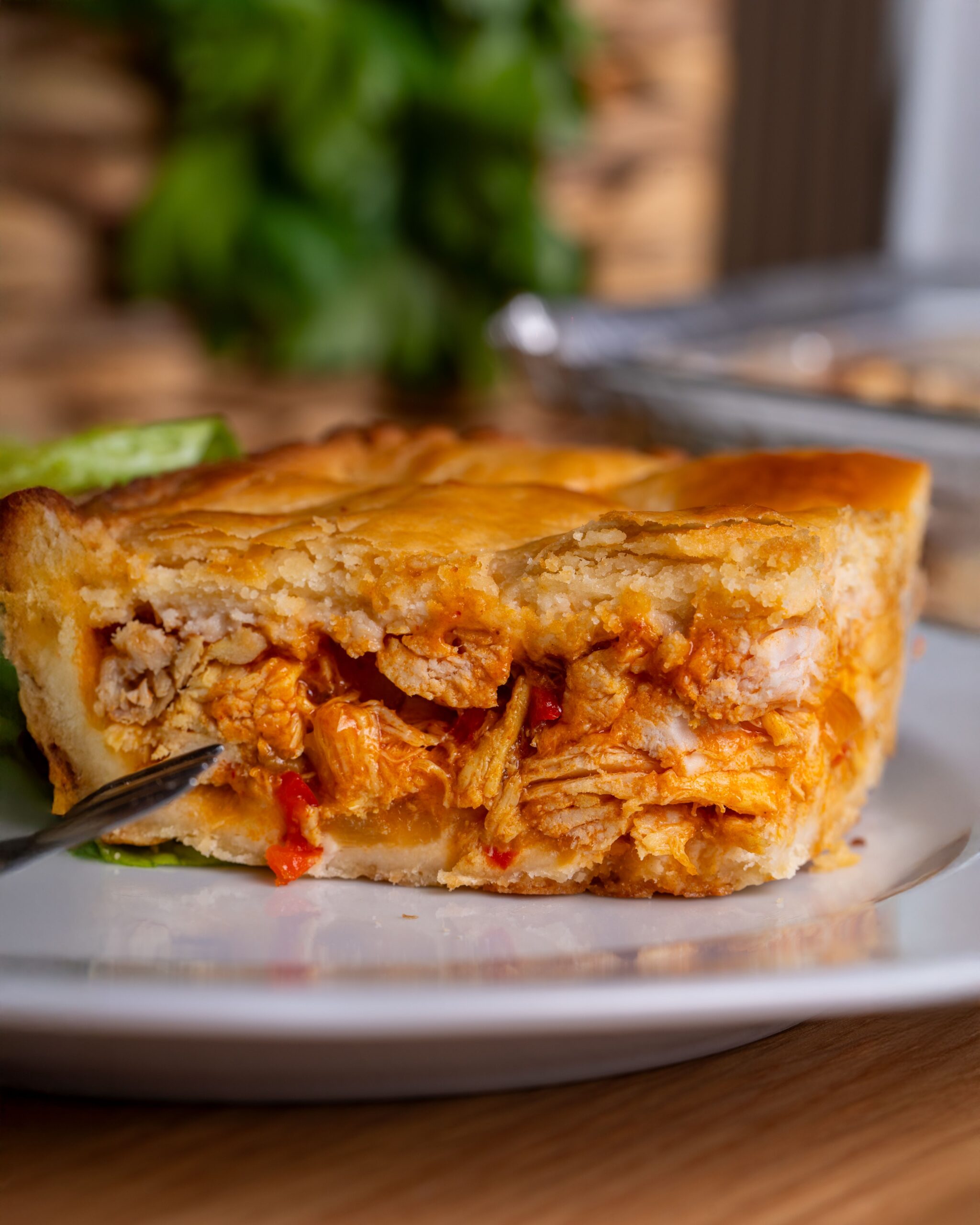 A slice of chicken pot pie with flaky crust served on a plate with a fork