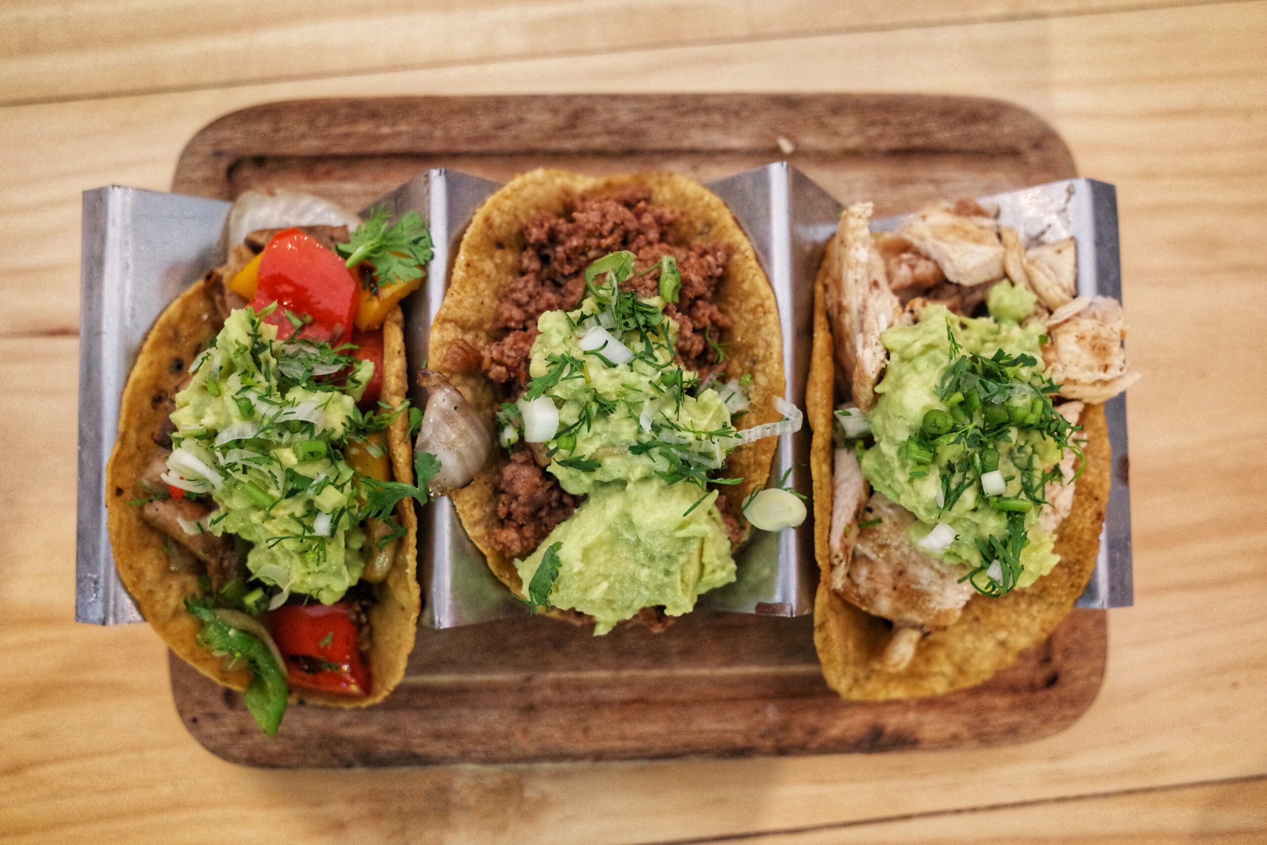 A trio of tacos with toppings, ready to serve
