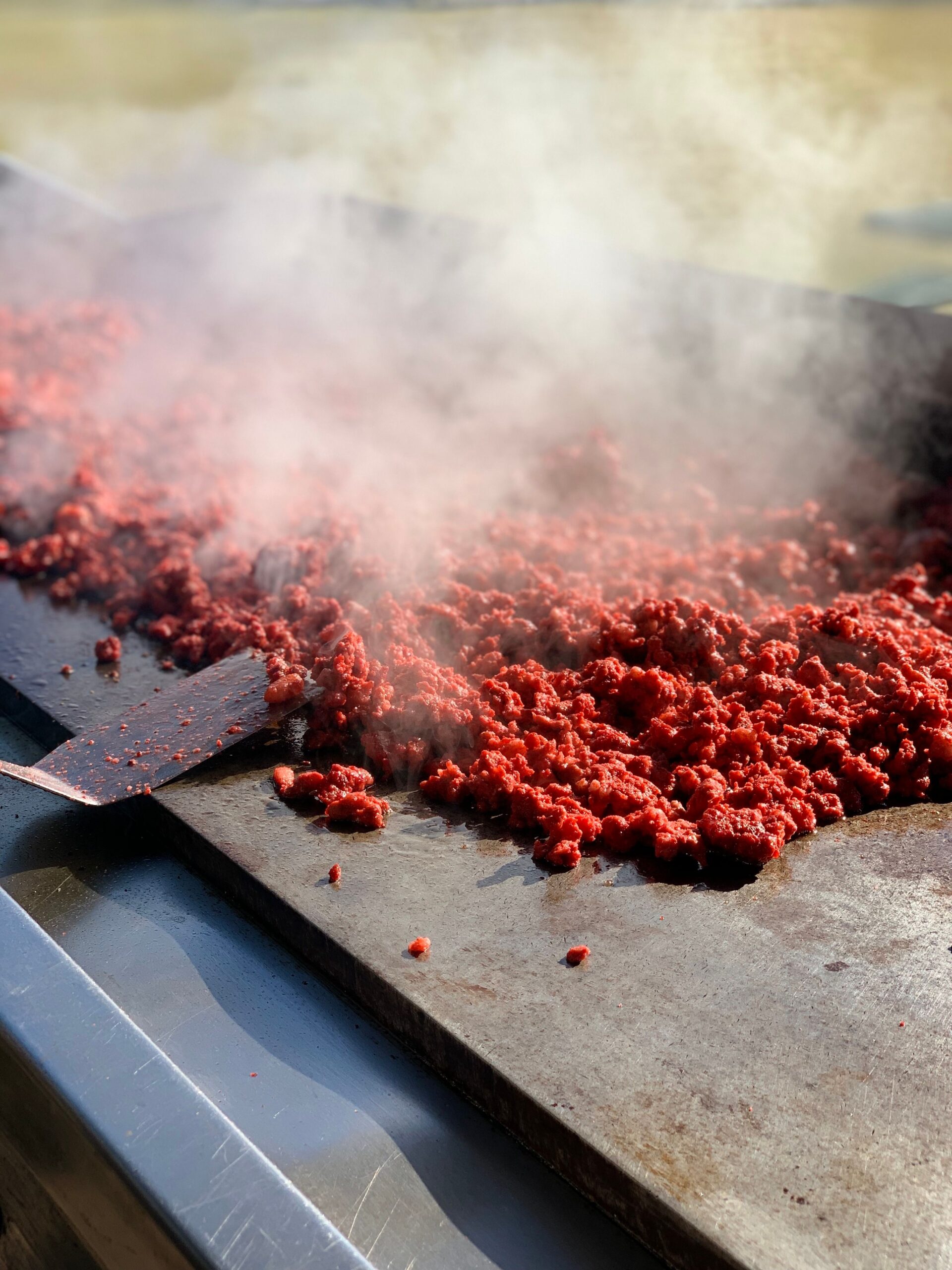 Seasoned ground beef browning on a griddle for taco filling