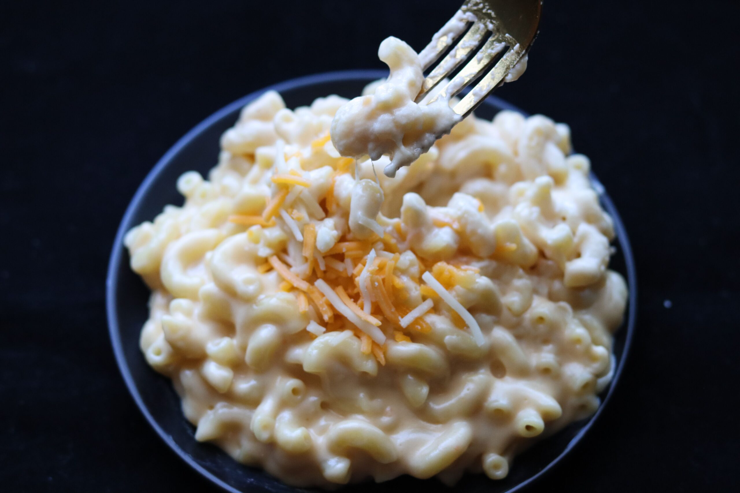 A fork lifting creamy mac and cheese from a bowl