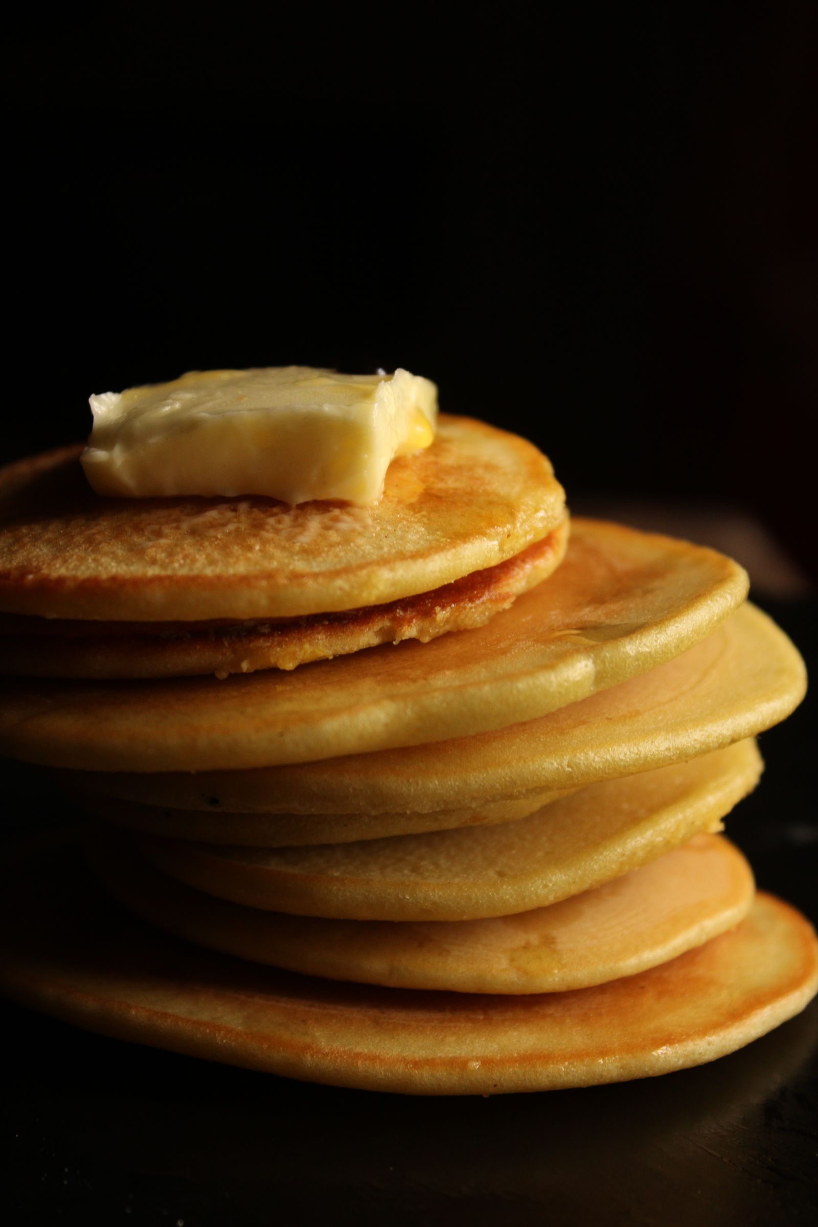 Stack of golden pancakes topped with a pat of melting butter