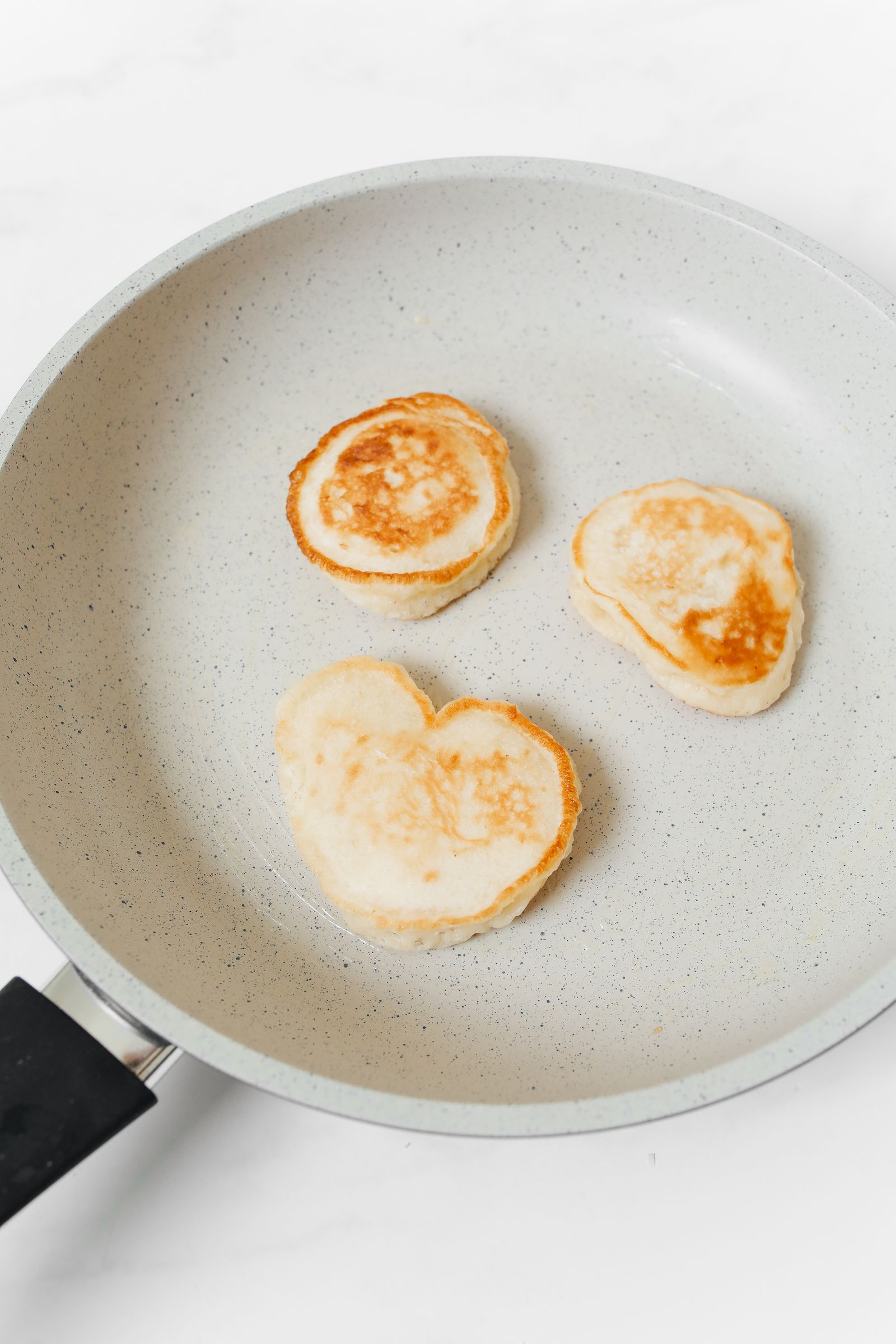 Pancakes cooking until golden brown in a nonstick frying pan