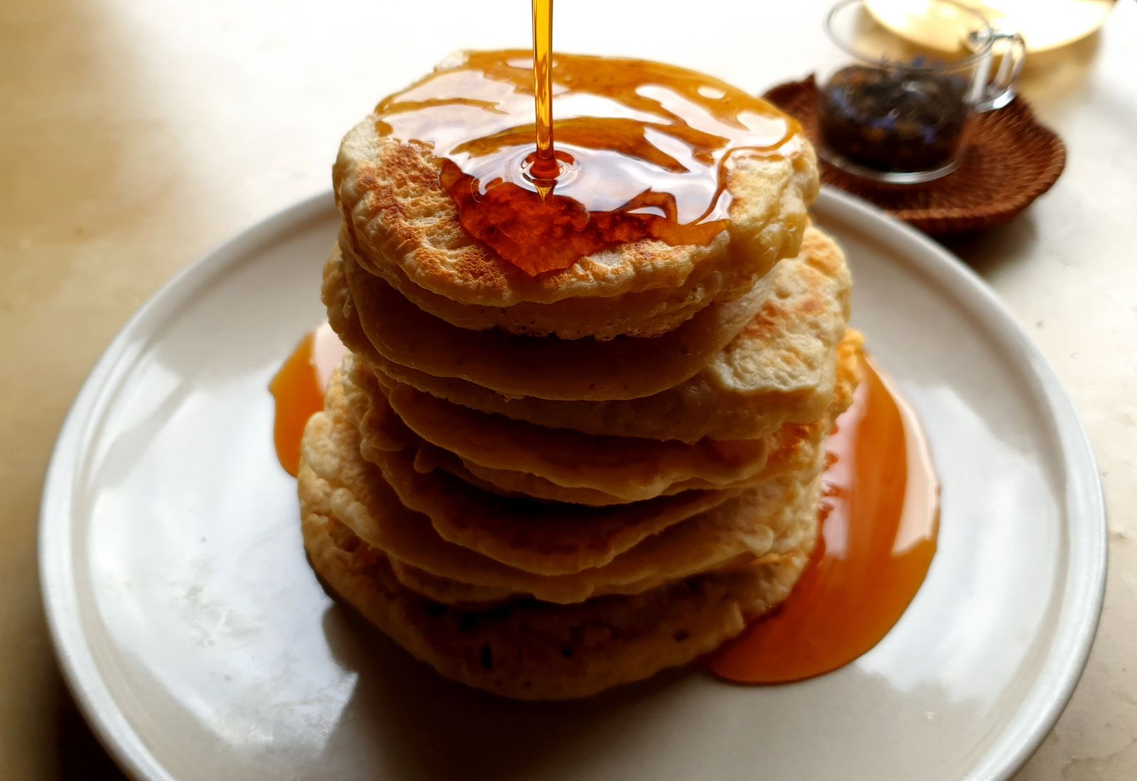 Maple syrup falling onto a tall stack of fluffy pancakes