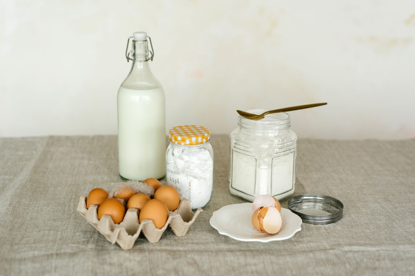 Rustic display of baking ingredients including eggs, milk and flour