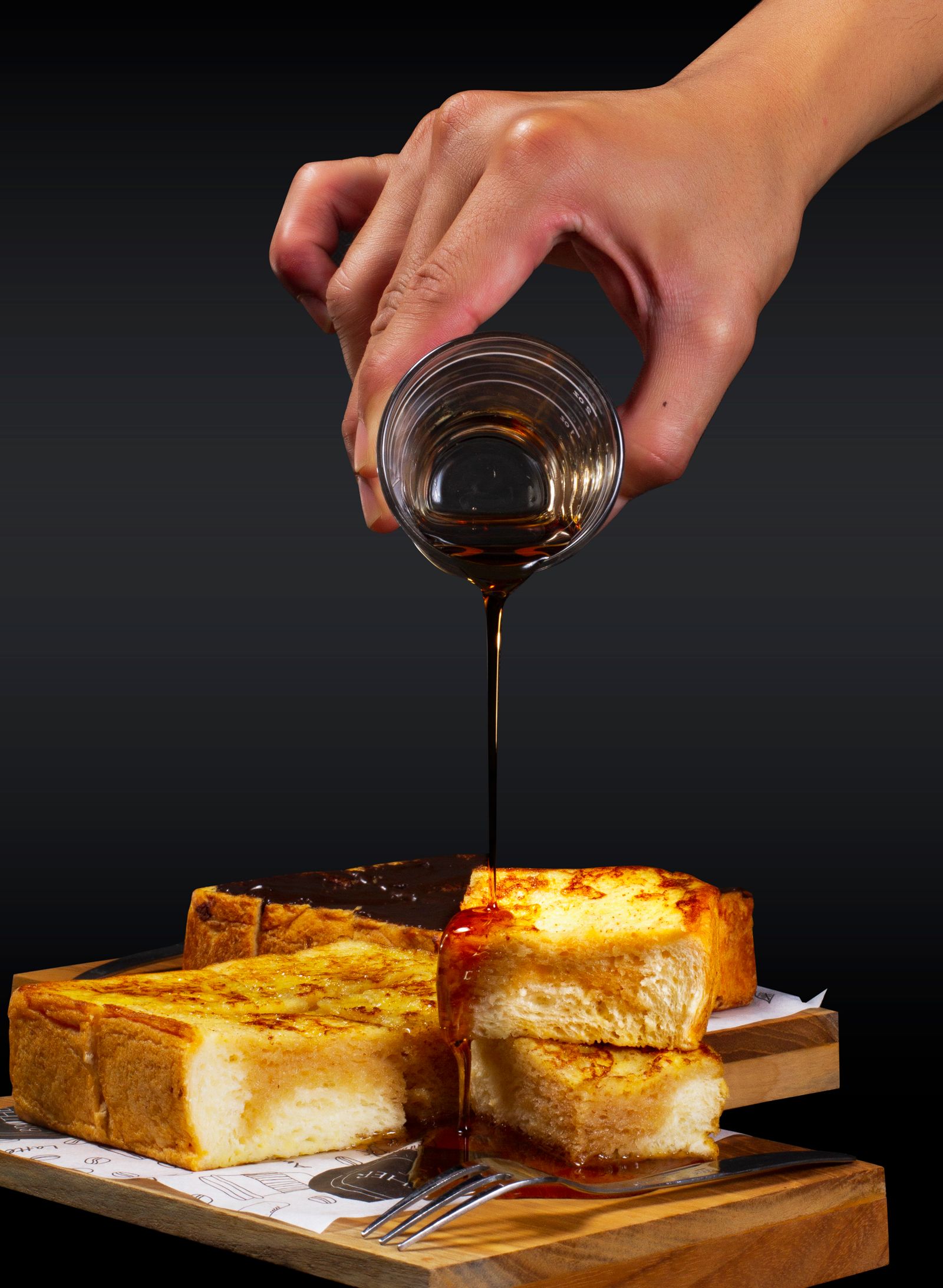 A close-up of syrup being poured over golden French toast