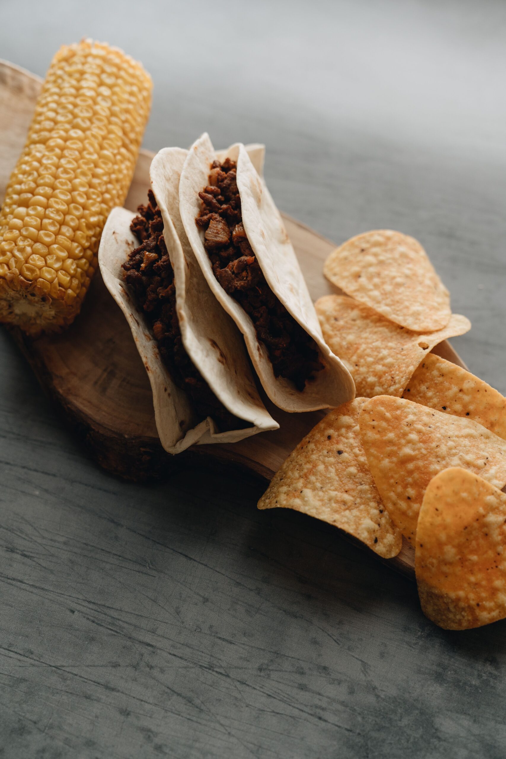 Ground beef tacos served with tortilla chips and corn on the cob