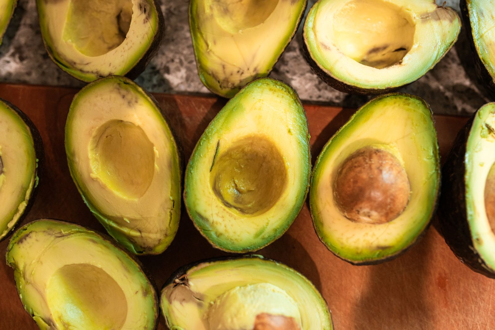 Top view of halved ripe avocados on a wooden surface