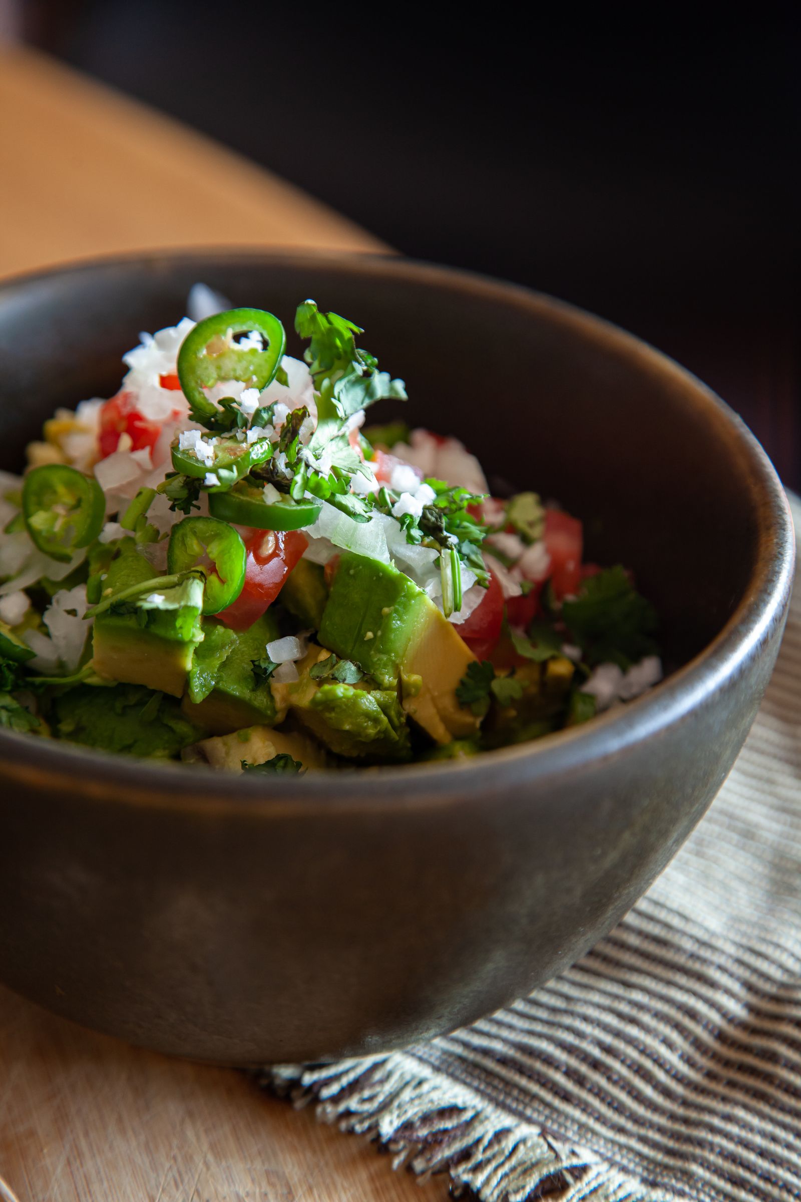 Close-up of fresh Mexican guacamole with avocado, chilli and cilantro in a bowl