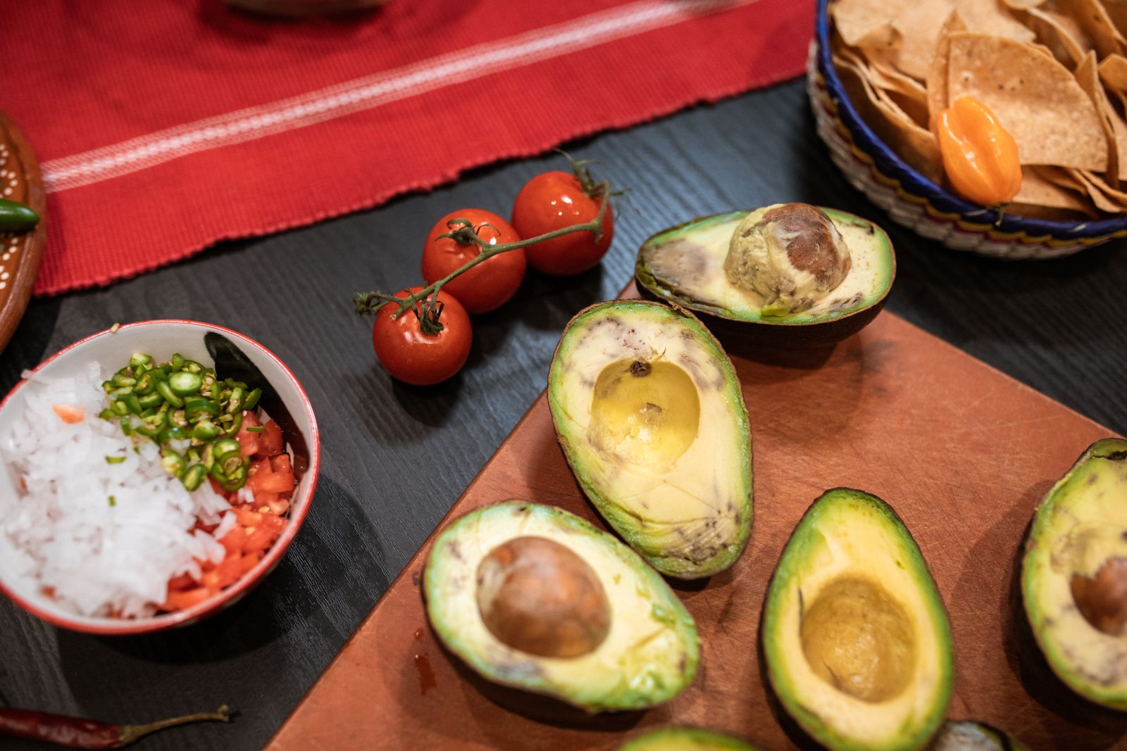 Overhead view of avocados, tomatoes and toppings for making fresh guacamole