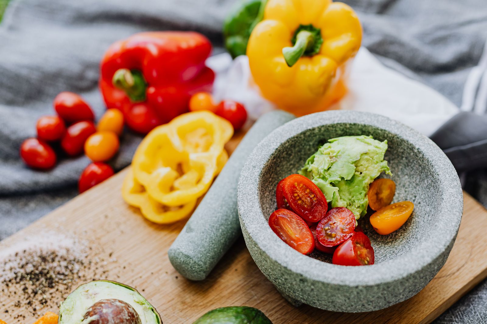 Close-up of fresh guacamole preparation with tomatoes, peppers and avocado in a mortar
