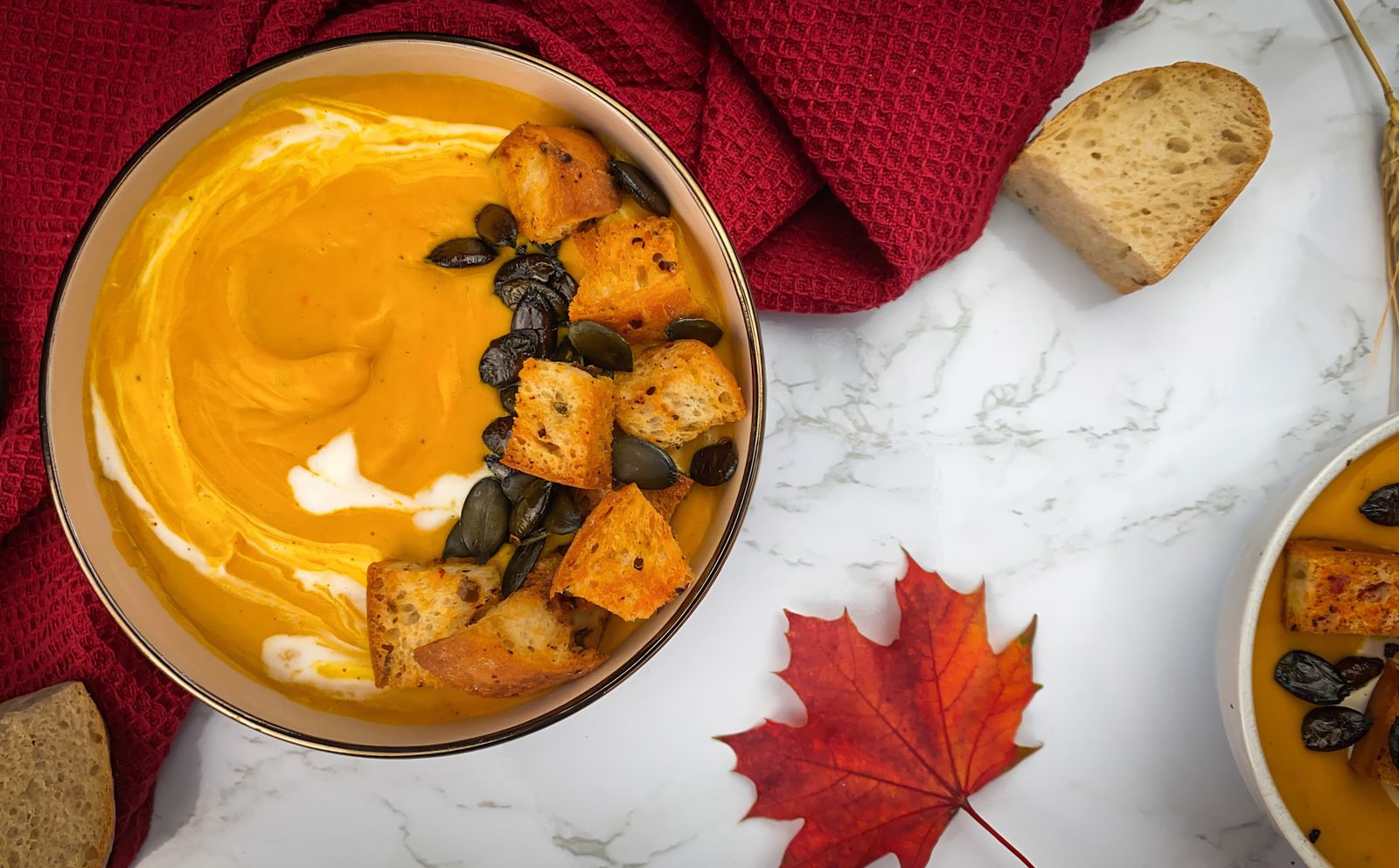 Bowl of creamy pumpkin soup topped with croutons and pumpkin seeds