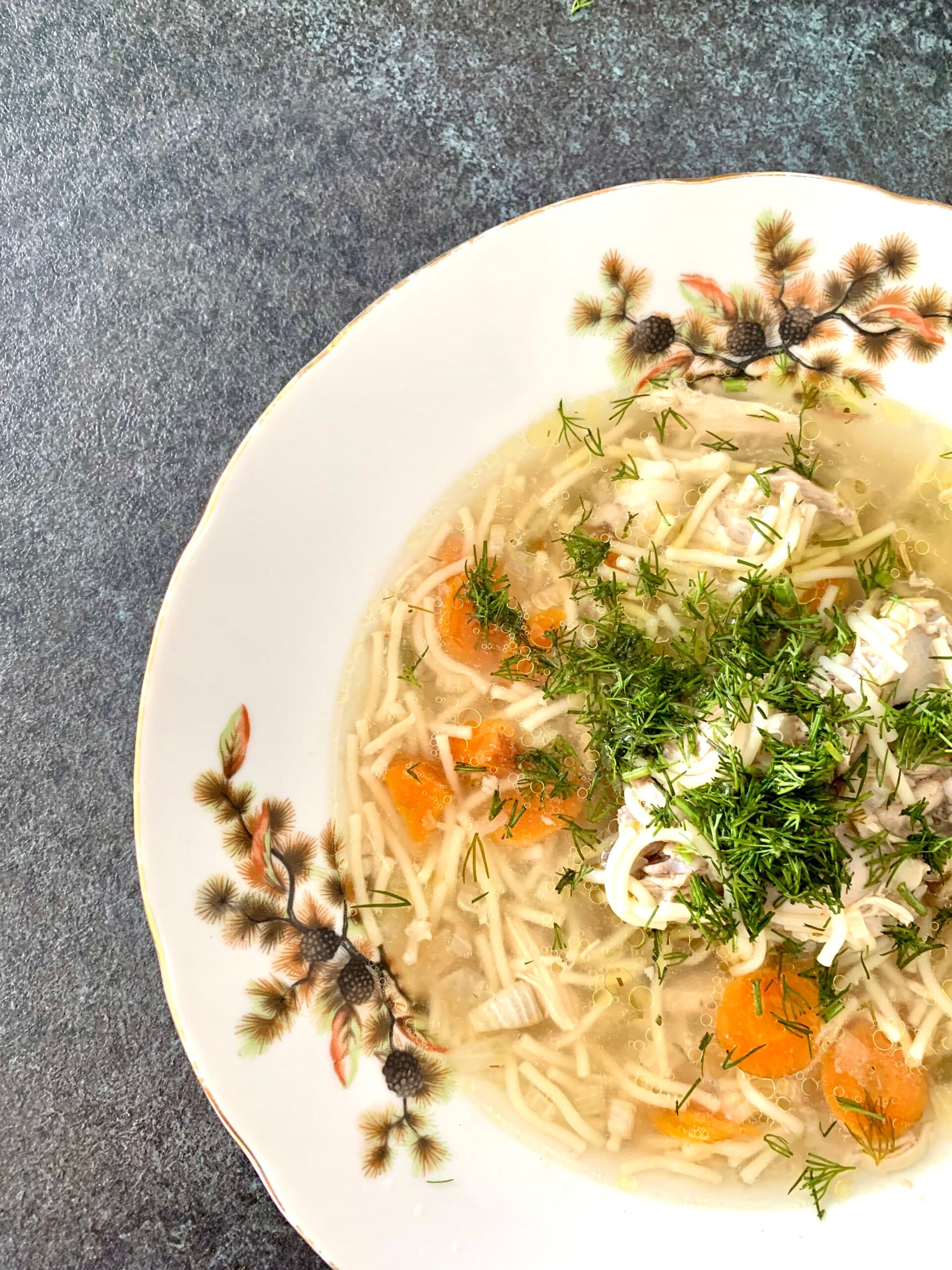 Homemade chicken noodle soup with carrots, noodles and fresh dill, top view