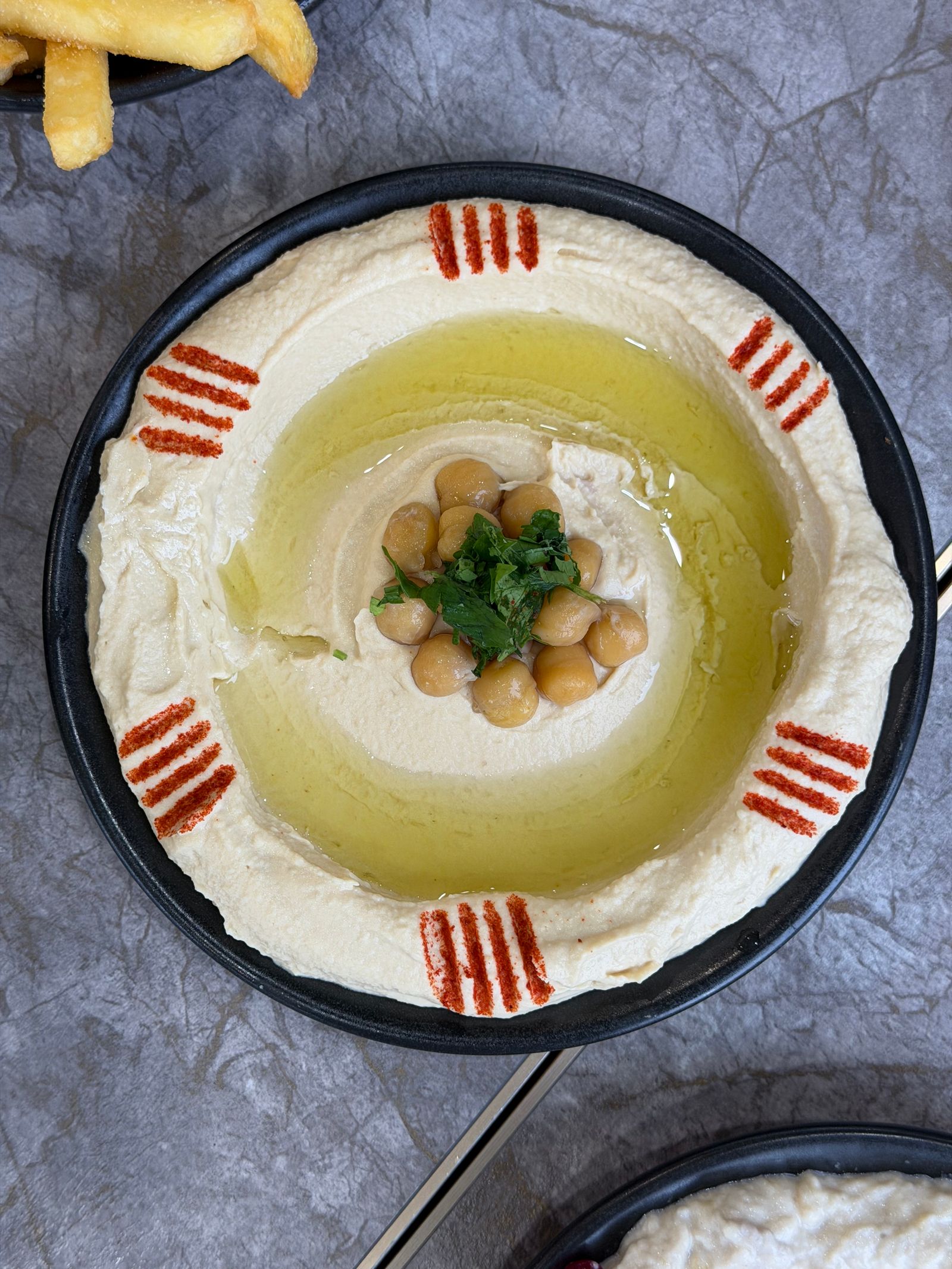 A vibrant plate of hummus garnished with chickpeas, olive oil and paprika