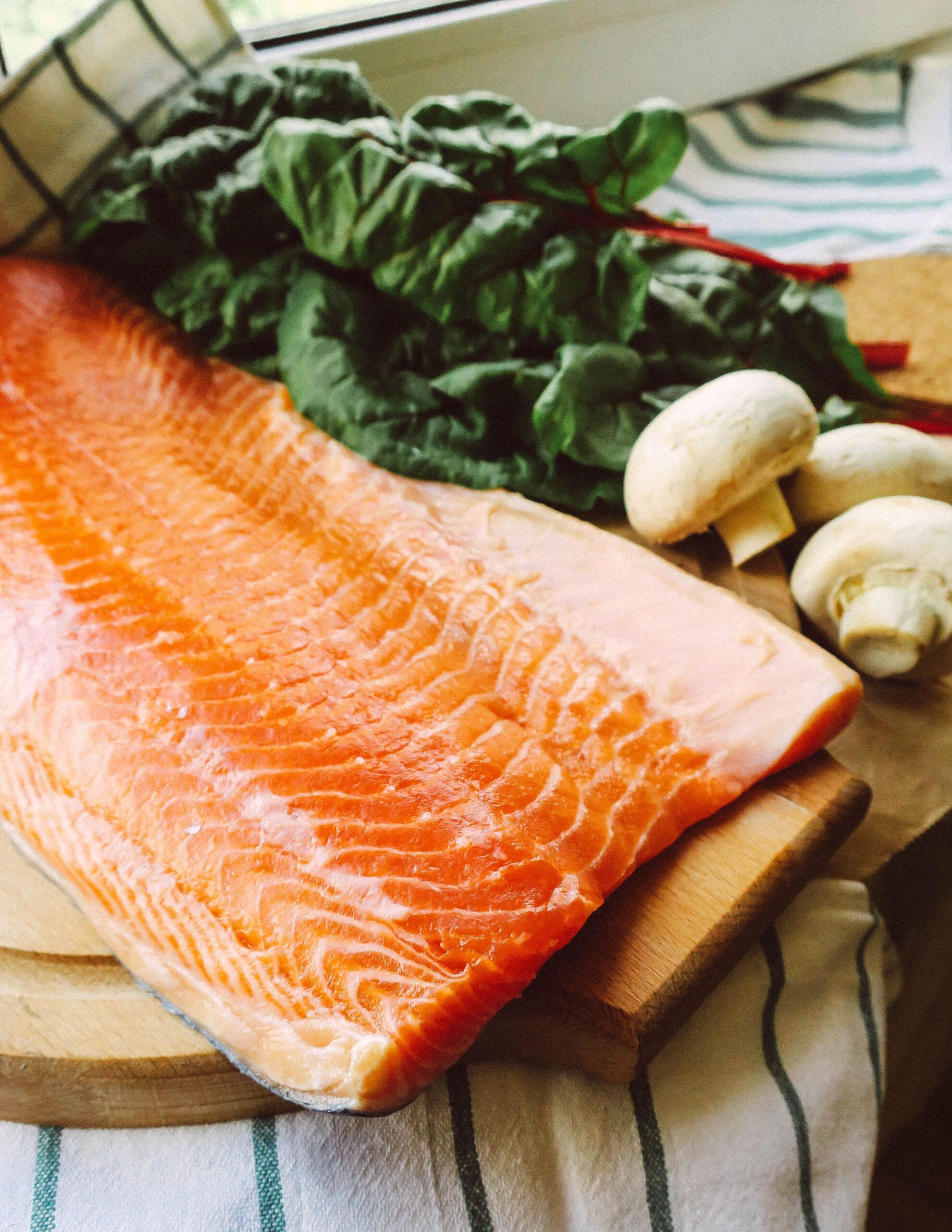 A raw salmon fillet on a cutting board, ready to cook