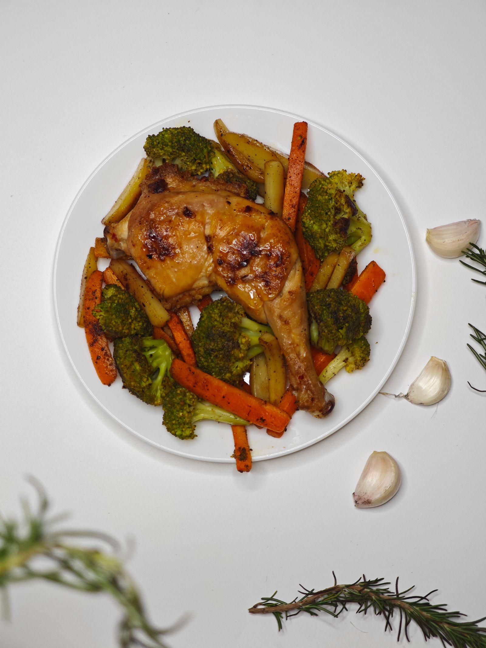 Roasted chicken leg served on a plate with carrots, broccoli and potatoes