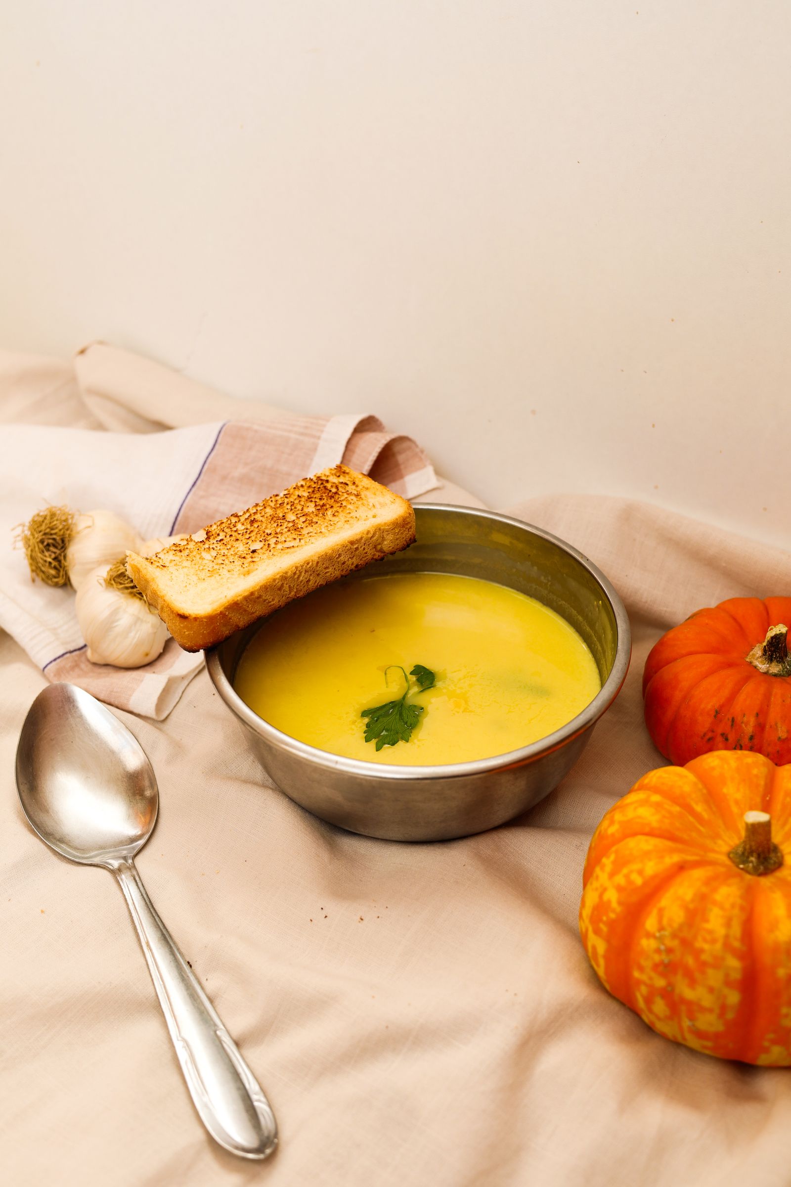 Warm pumpkin soup served with toast and roasted garlic
