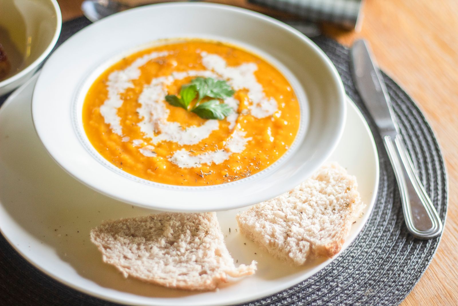 Creamy pumpkin soup garnished with cream and parsley, served with bread