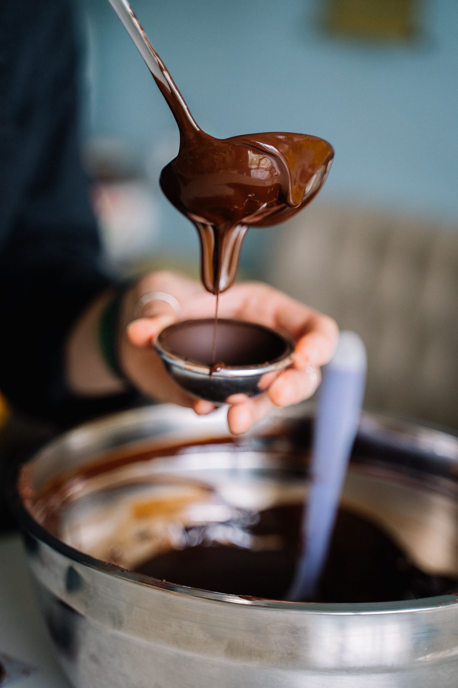 Melted chocolate being poured from a spoon into a small bowl